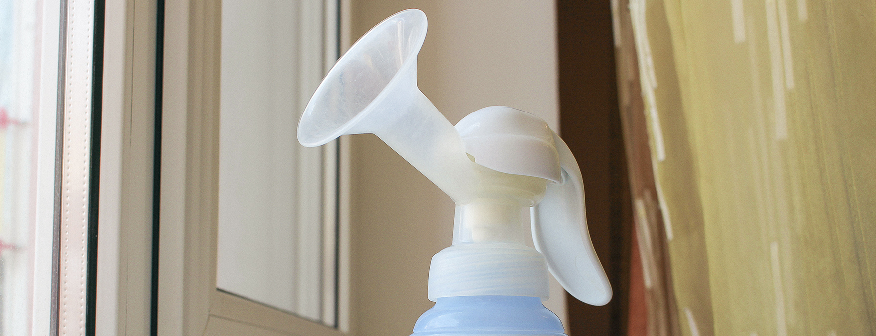 Breast pump and bottle of milk on the windowsill