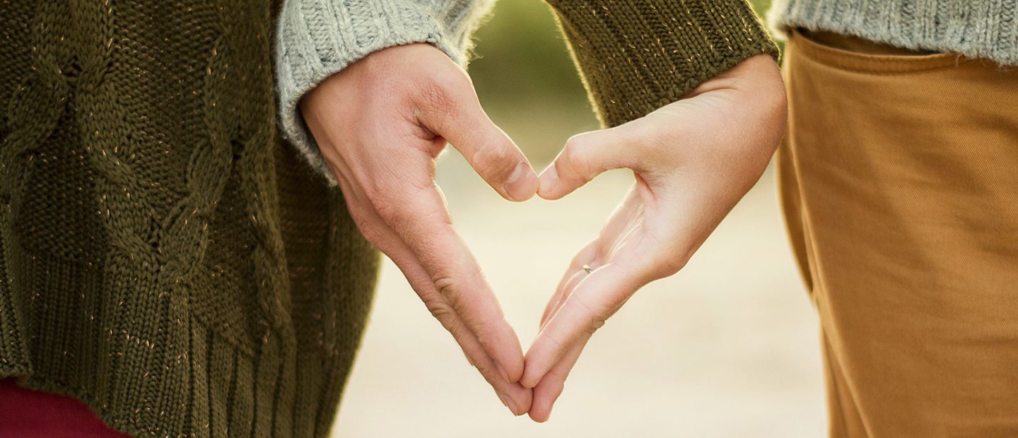 Couple make a heart shape with their hands