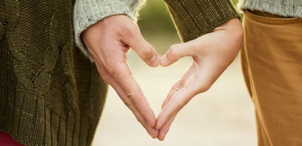 Couple make a heart shape with their hands