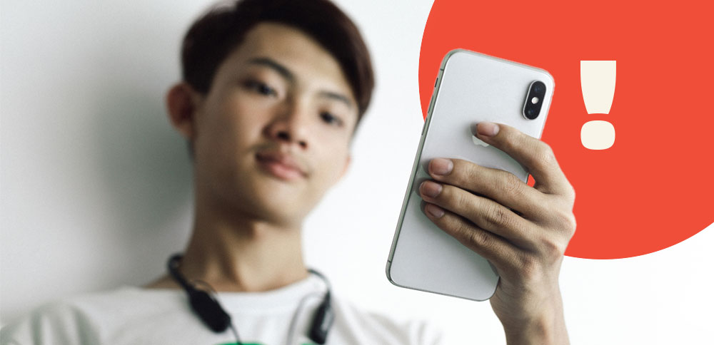 A person looking at their phone with a red circle in the background and a large exclamation mark.