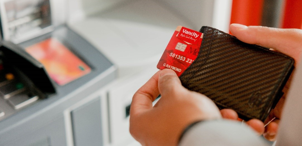 A close-up of a person’s hand reaching into their wallet for their Vancity MEMBER CARD® debit card.