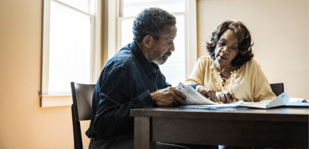 A couple sitting together at their kitchen table reviewing their finances.