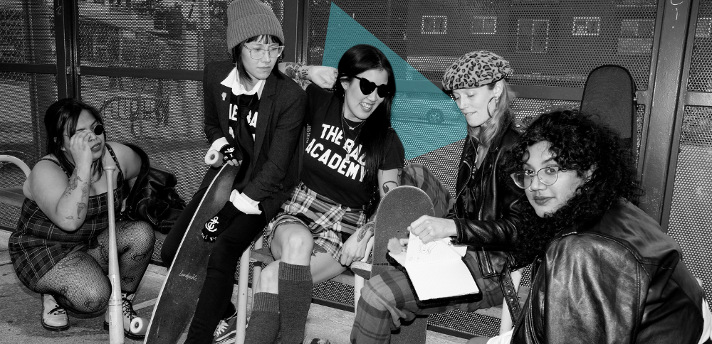 Black-and-white photo of Amanda Kao at the center with a group of women and gender-diverse individuals, some holding skateboards, wearing punk-inspired outfits. 'The Bad Academy' is printed on their shirts, reflecting creativity and community.
